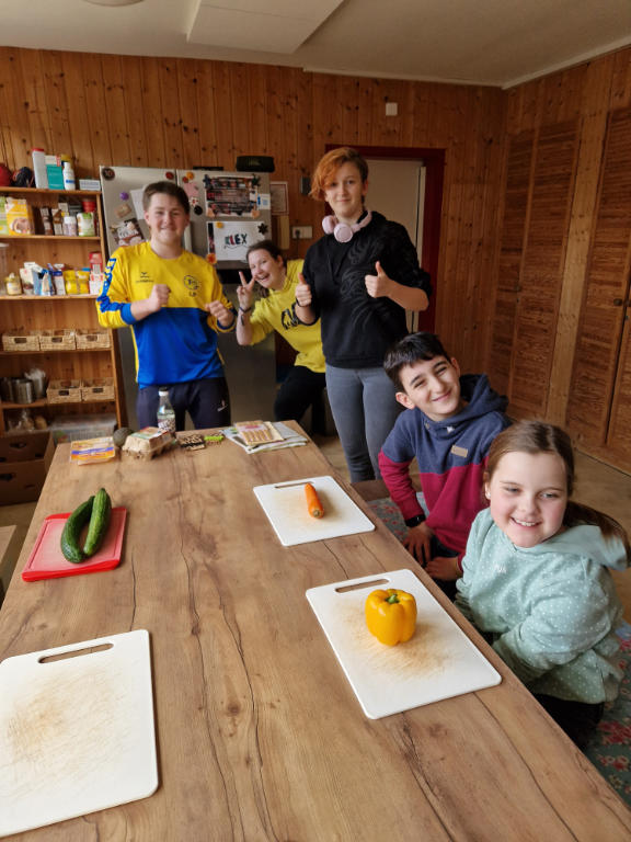Kinder am Küchentisch mit Schneidebrettern und frischen Zutaten
